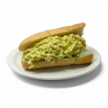 A vegan egg salad sandwich on a soft grinder roll with lettuce, presented on a red and white checkered paper.